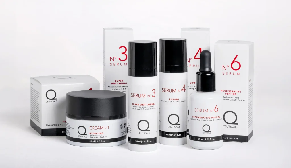 A collection of white and black skincare products, including creams and serums, from a brand called Q Ceuticals. Each product is labeled with a different number, such as 3 and 6, and the packaging highlights various skincare benefits.